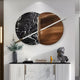 Giant Sculptures Lunaris Black Marble & Bronze LED Wall Art showcases a circular design with a diagonal dividing rod. Below it sits a white cabinet adorned with a vase, books, yellow figurine, and dark-toned human bust sculpture against a modern neutral backdrop.