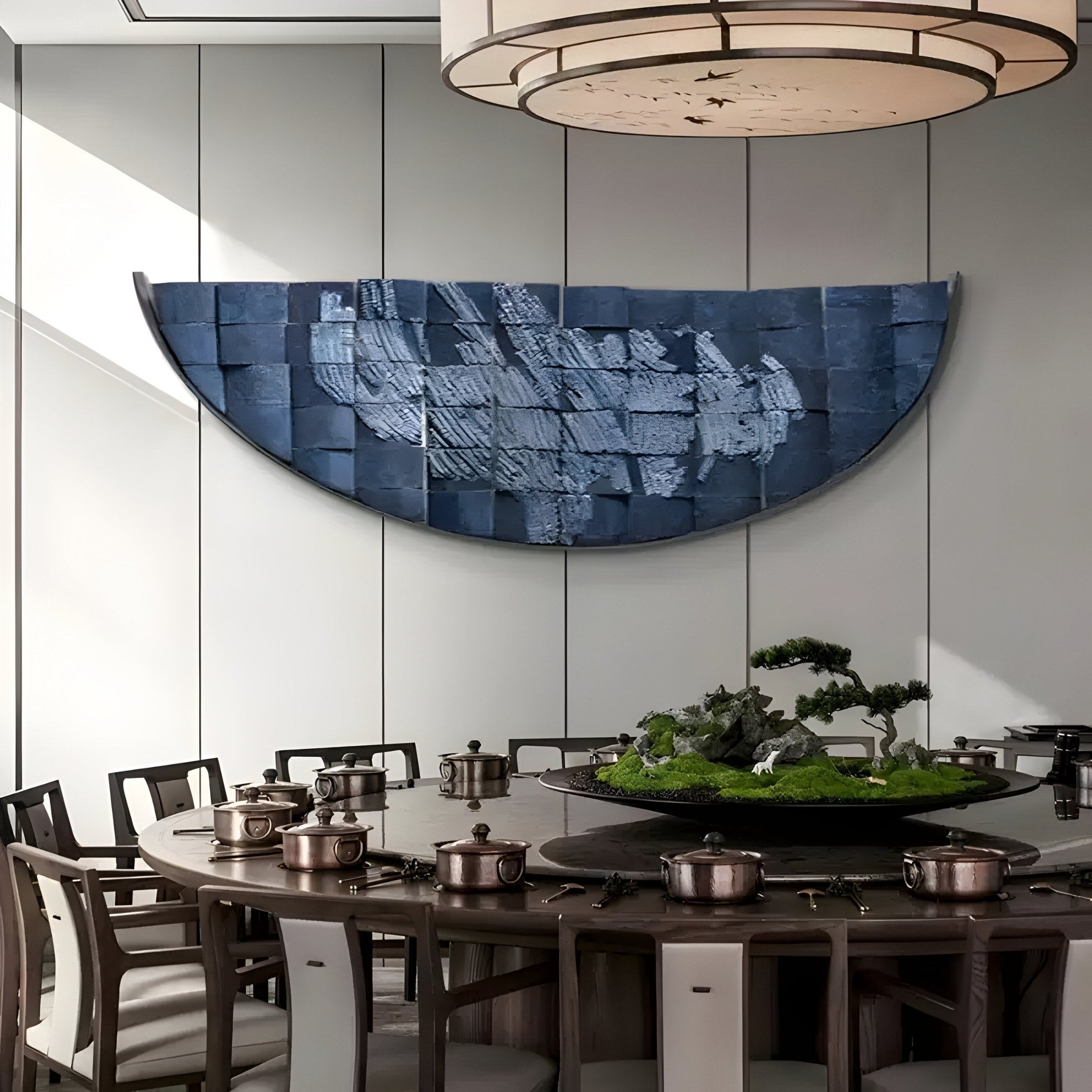 A modern dining room with a round table set for a meal features copper pots and a moss and plant centerpiece. Above the table, the Arcana Midnight Blue Textured Mosaic Half-Moon 3D Wall Art by Giant Sculptures adds depth and elegance to the room.