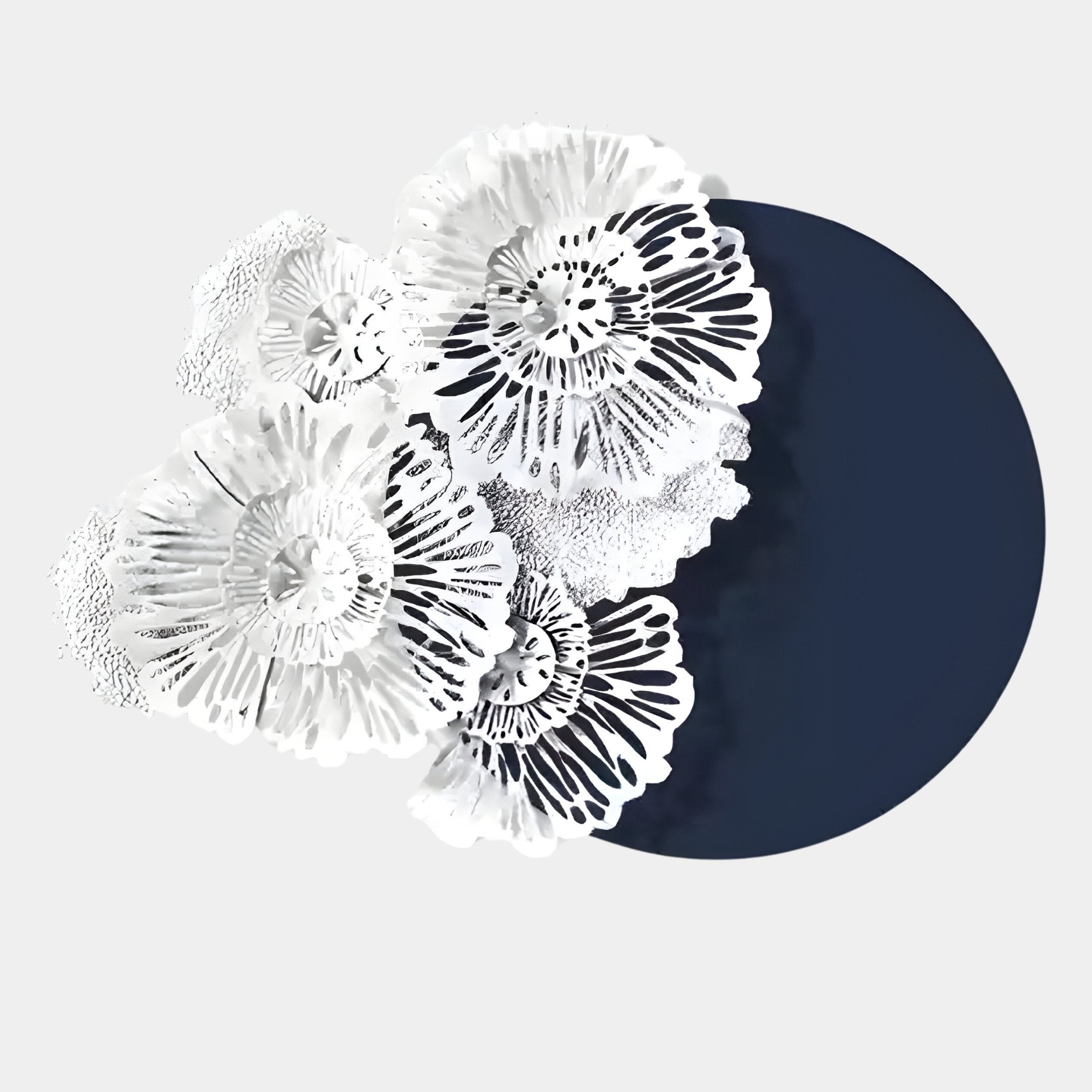 The Fleur Halo Navy Blue Round White Metal Floral Decorative Wall Art by Giant Sculptures features intricate white floral shapes overlapping a bold navy circle, adding striking decorative flair against a light gray background.