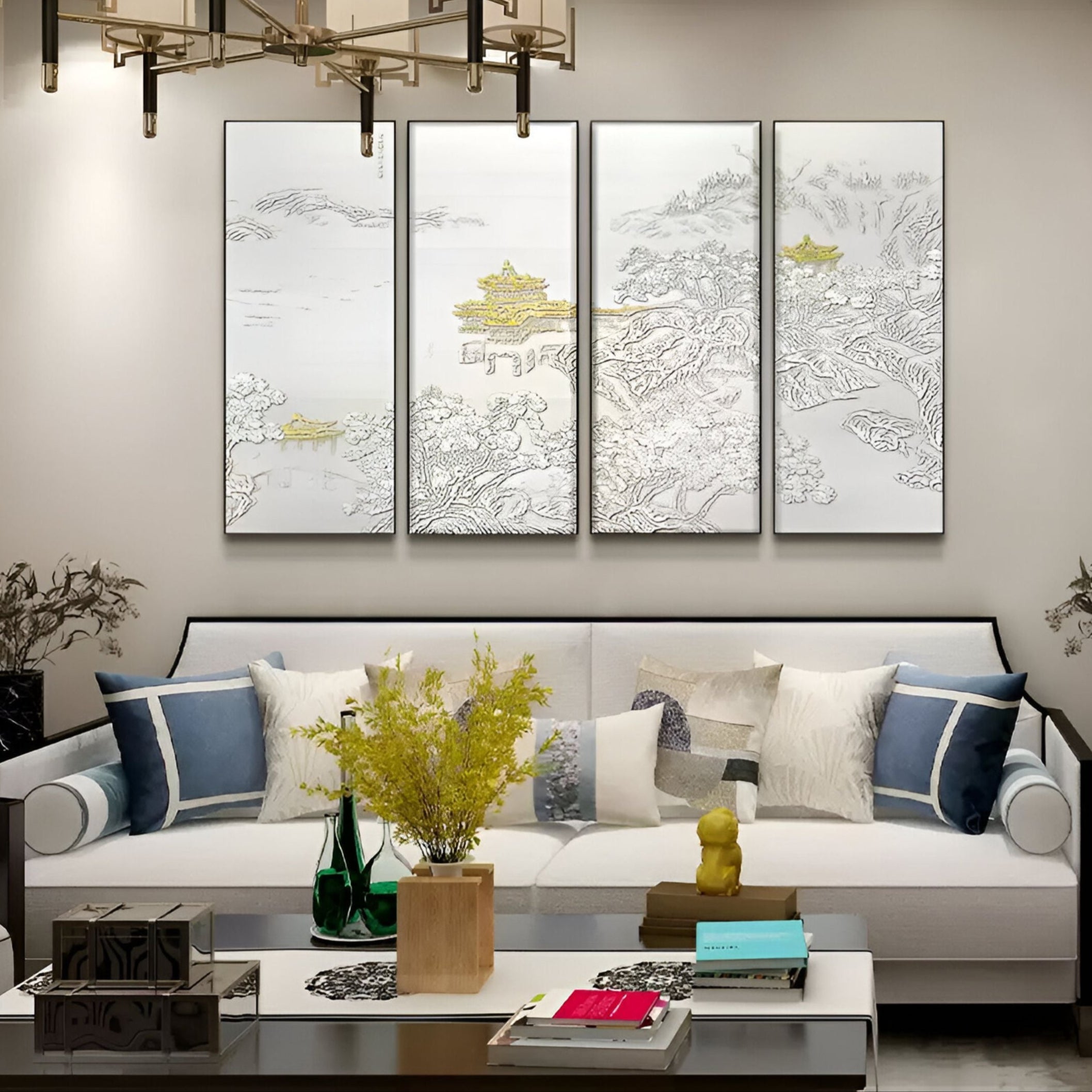 A modern living room showcases a white sofa with blue and gray cushions. Above it, the Velantra Harmonious Multi-Panel Silk Art by Giant Sculptures depicts serene landscapes with subtle gold and 3D accents. A coffee table holds decor items and a vase of yellow flowers, enhancing the rooms charm.