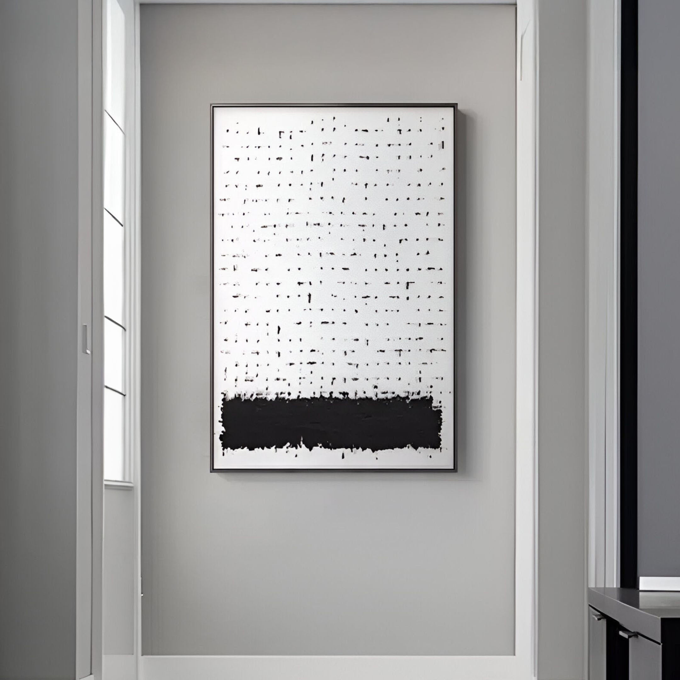 The Ethore Textured Minimalist Silk Art Panel in Black and White by Giant Sculptures hangs on a gray wall in a well-lit room, showcasing a white background with scattered black dots at the top and a bold black horizontal band at the bottom.