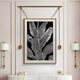 The Glacia Monochrome Botanical Crystal Hanging Framed Wall Art by Giant Sculptures hangs centered between two modern sconces above a white console table with books, capturing minimalist design and contemporary craftsmanship.