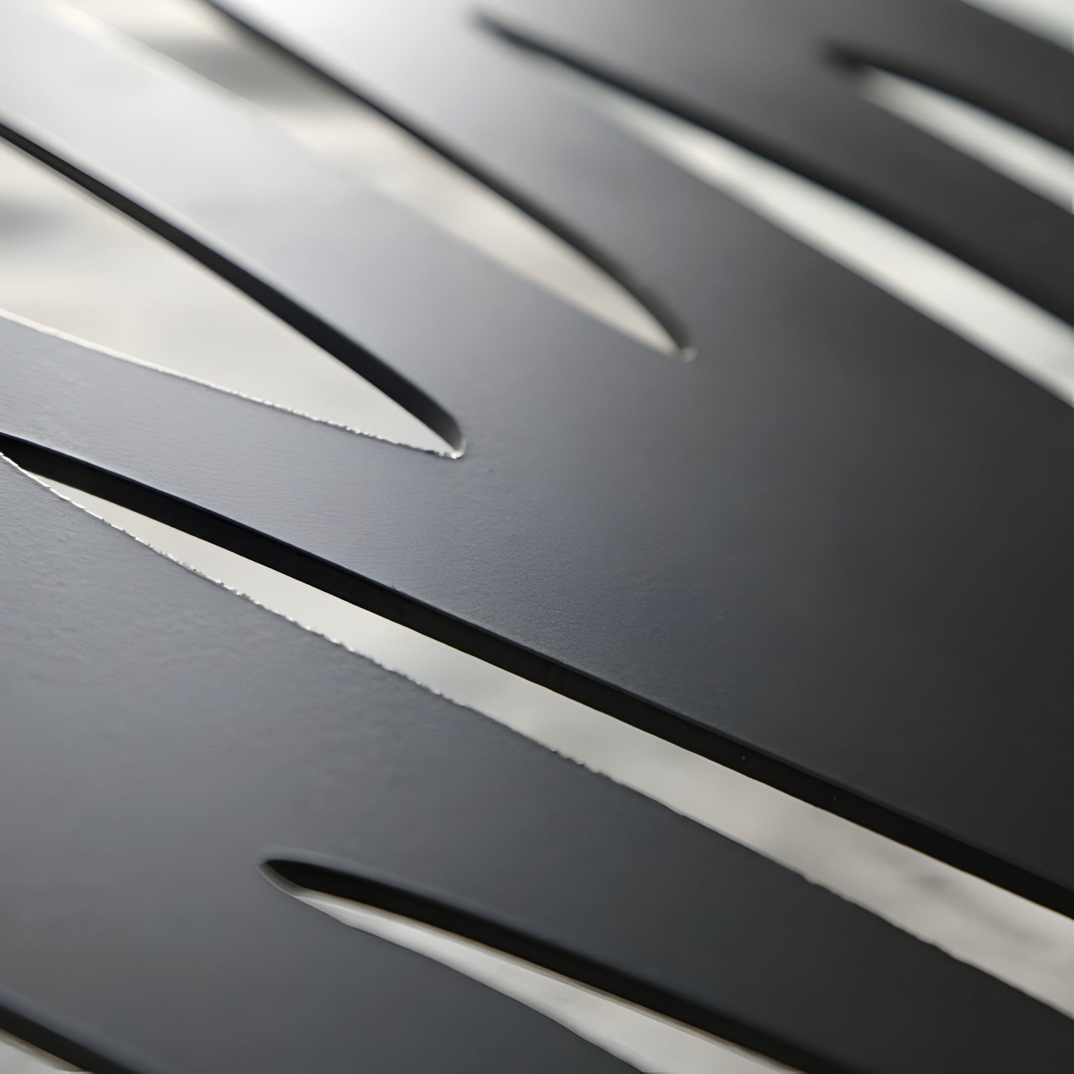 Close-up of Oscura Stratum by Giant Sculptures: sleek, black, curved blades forming abstract metal wall art. The texture and soft shadows reflect light subtly off the smooth layered black metal, ideal for modern interiors.