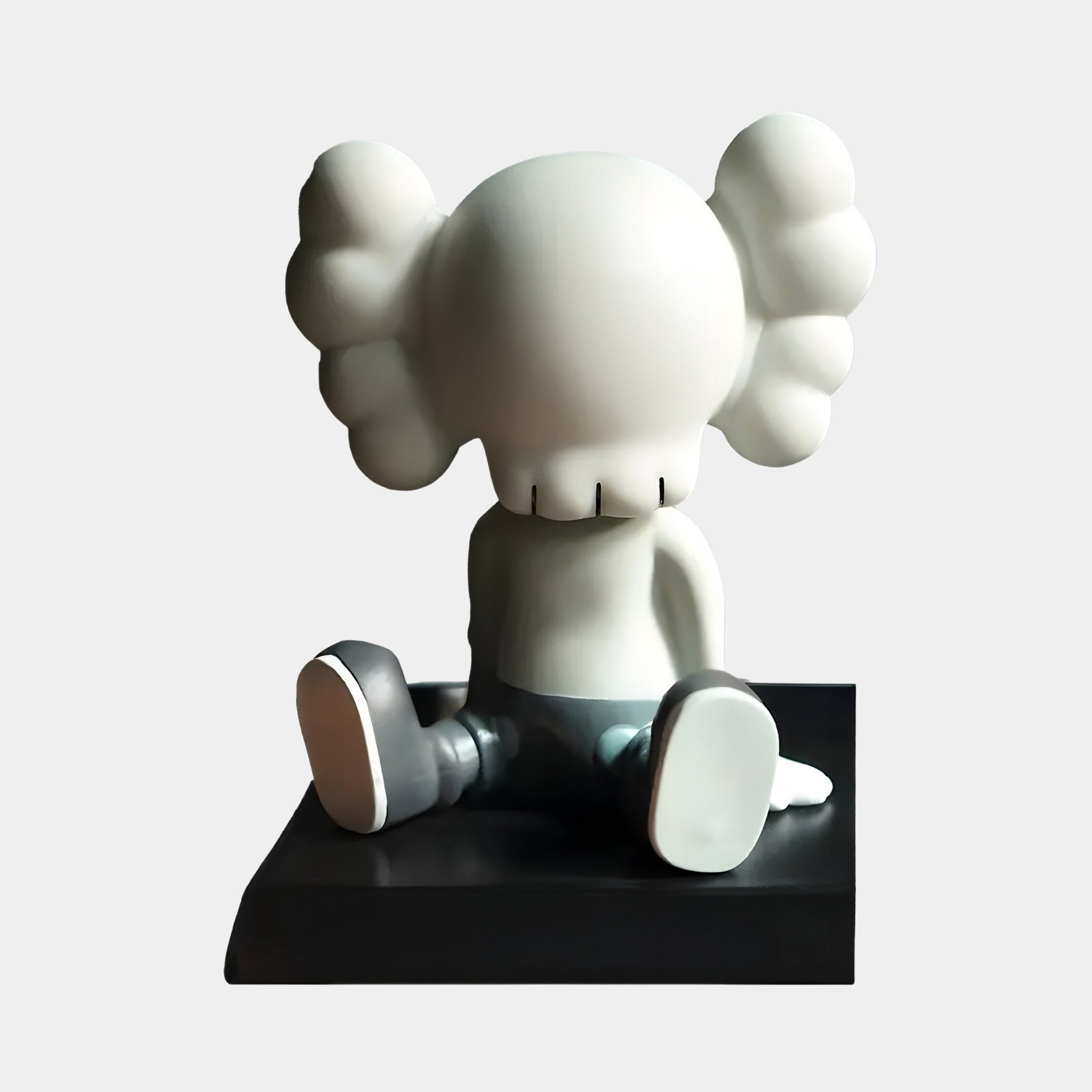 The Dove Grey I Iconify Bobblehead Figure by Giant Sculptures is a 10cm resin figure featuring a seated character with large ears and an unseen face in subtle gray tones, elegantly placed on a black platform, epitomizing modern aesthetics.