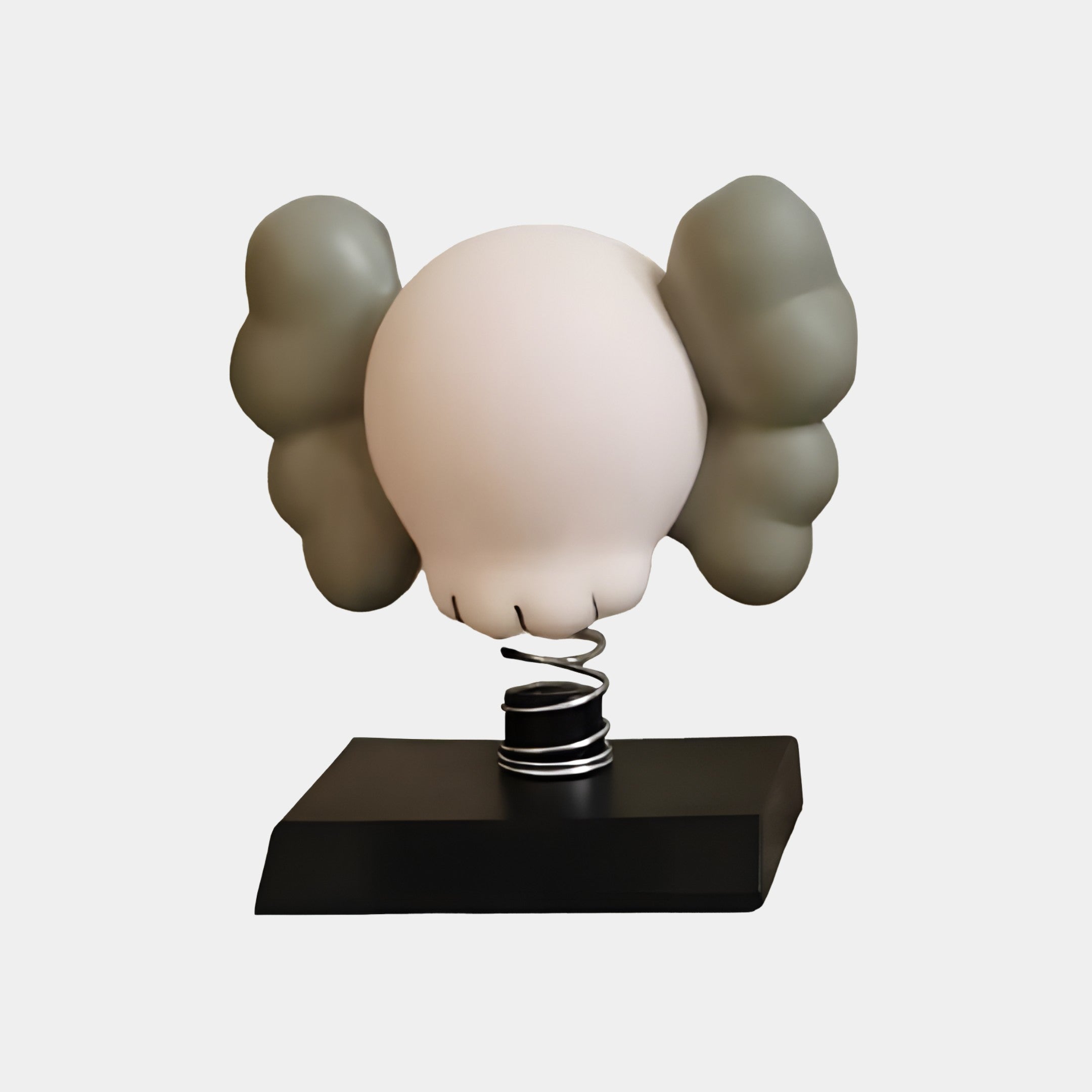 The Soft Ivory Iconify Bobblehead Figure by Giant Sculptures is a 10cm minimalist resin piece featuring a sleek black base and a head on a spring with large gray ears, resembling an ivory bobblehead without facial features.