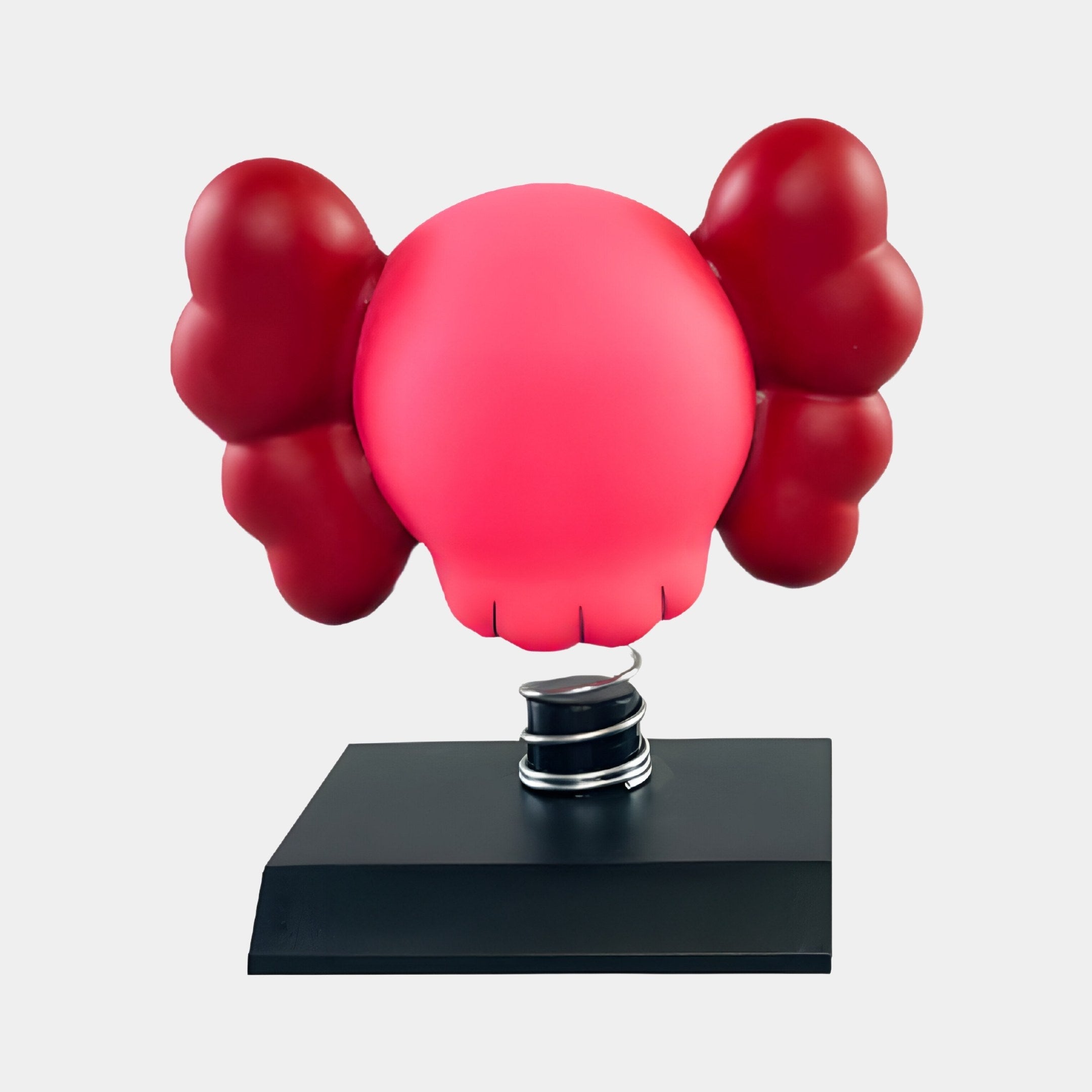 The Blush Ruby Iconify Bobblehead Figure by Giant Sculptures is a red, balloon-like sculpture with large ears and a simplified face on a black rectangular base, resembling a cartoonish figure with puffy arms that capture its whimsical charm.