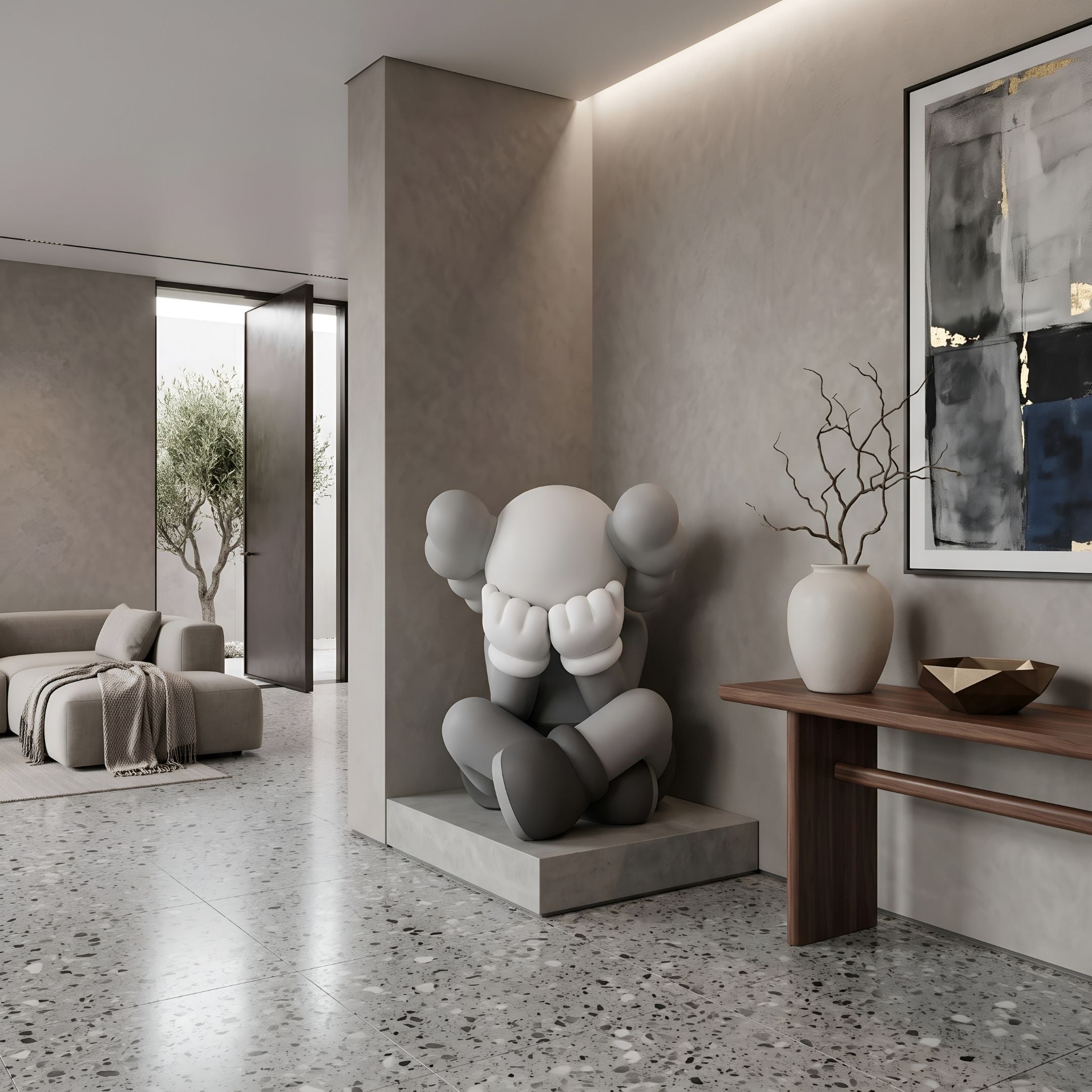 Slate Grey Iconify Sorrow Sculpture, 92cm, seated figure covering face with rounded ears, on a plinth in a living room beside a console table and wall art.
