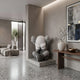 Slate Grey Iconify Sorrow Sculpture, 92cm, seated figure covering face with rounded ears, on a plinth in a living room beside a console table and wall art.