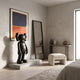 Midnight Black Iconify Standing Sculpture (100cm) on a stone platform beside a mirror, in a bedroom with abstract wall art and a console table.