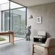 Soft Grey Iconify Standing Sculpture, 100cm, resin figure with crossed eyes in a modern living room beside a black-and-white armchair and floor lamp.