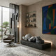 Soft Grey Iconify Peace Sculpture, 110cm, reclining figure on a dark platform in a living room with shelving, armchair, and abstract wall art.