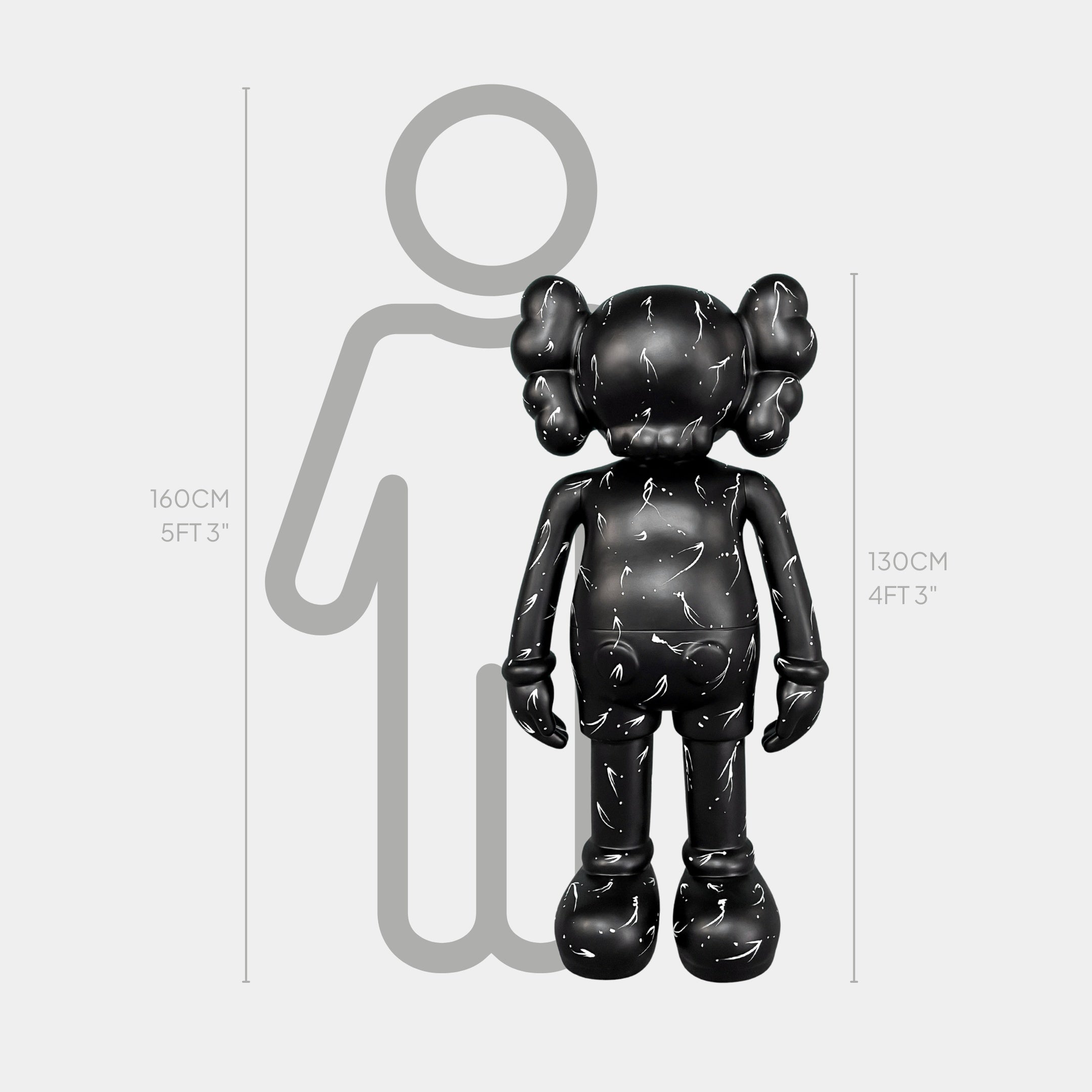 The Black Stone Iconify Standing Sculpture by Giant Sculptures is a 130cm (4ft 3in) tall, black, cartoon-inspired art piece shown in front of a 160cm (5ft 3in) person outline for scale.