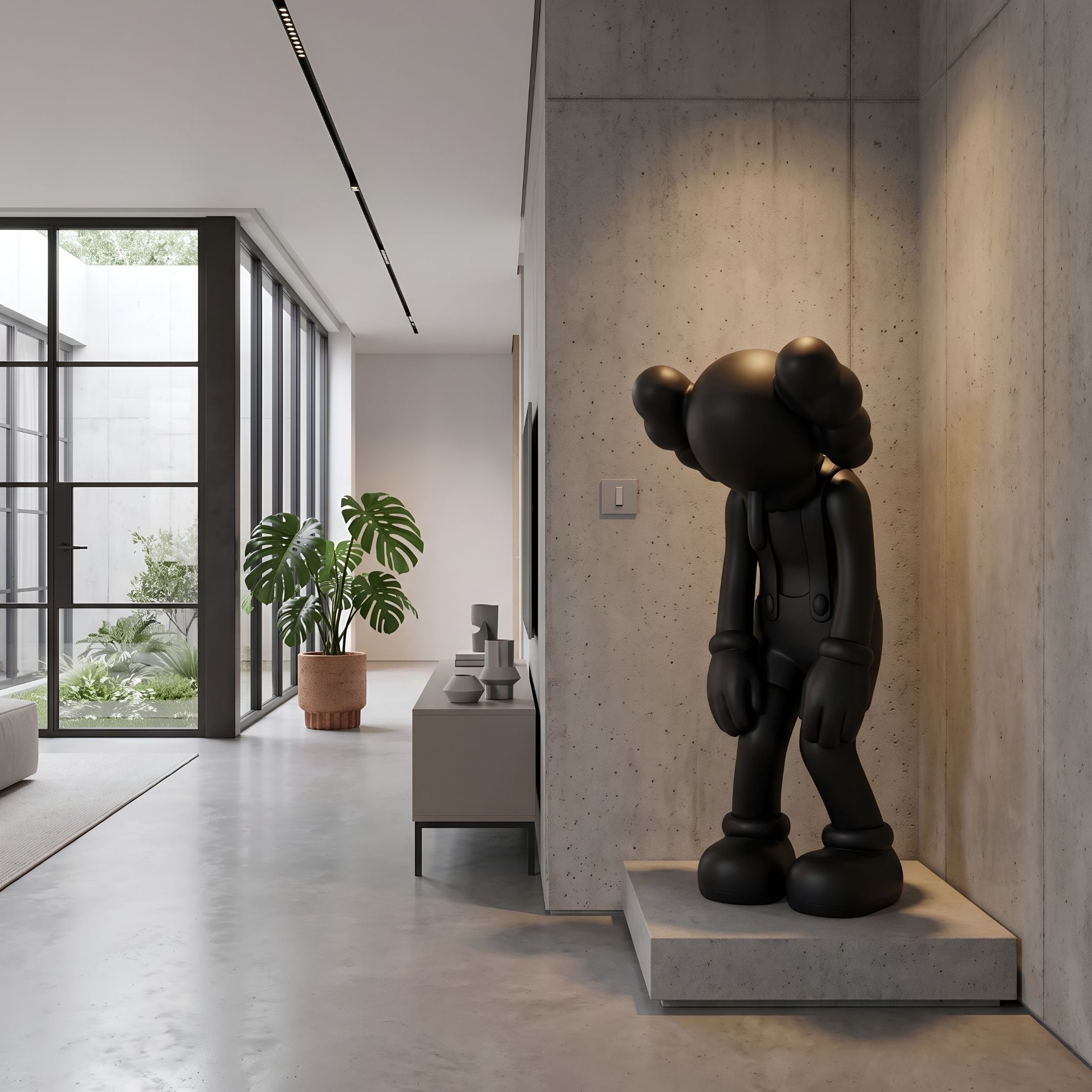 Midnight Black Iconify Burden Sculpture, 130cm, standing in a modern hallway on a concrete plinth against a textured wall, near a potted plant and console table.