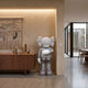 Soft Grey Iconify II Dance Sculpture, 130cm, standing figure with crossed-bones ears and gloved hands, shown beside a wooden sideboard in a neutral-toned living space.