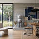 Soft Grey Iconify III Dance Sculpture, 130cm, on a concrete platform in a dining area with rattan chairs, wood table, and woven wall hanging.