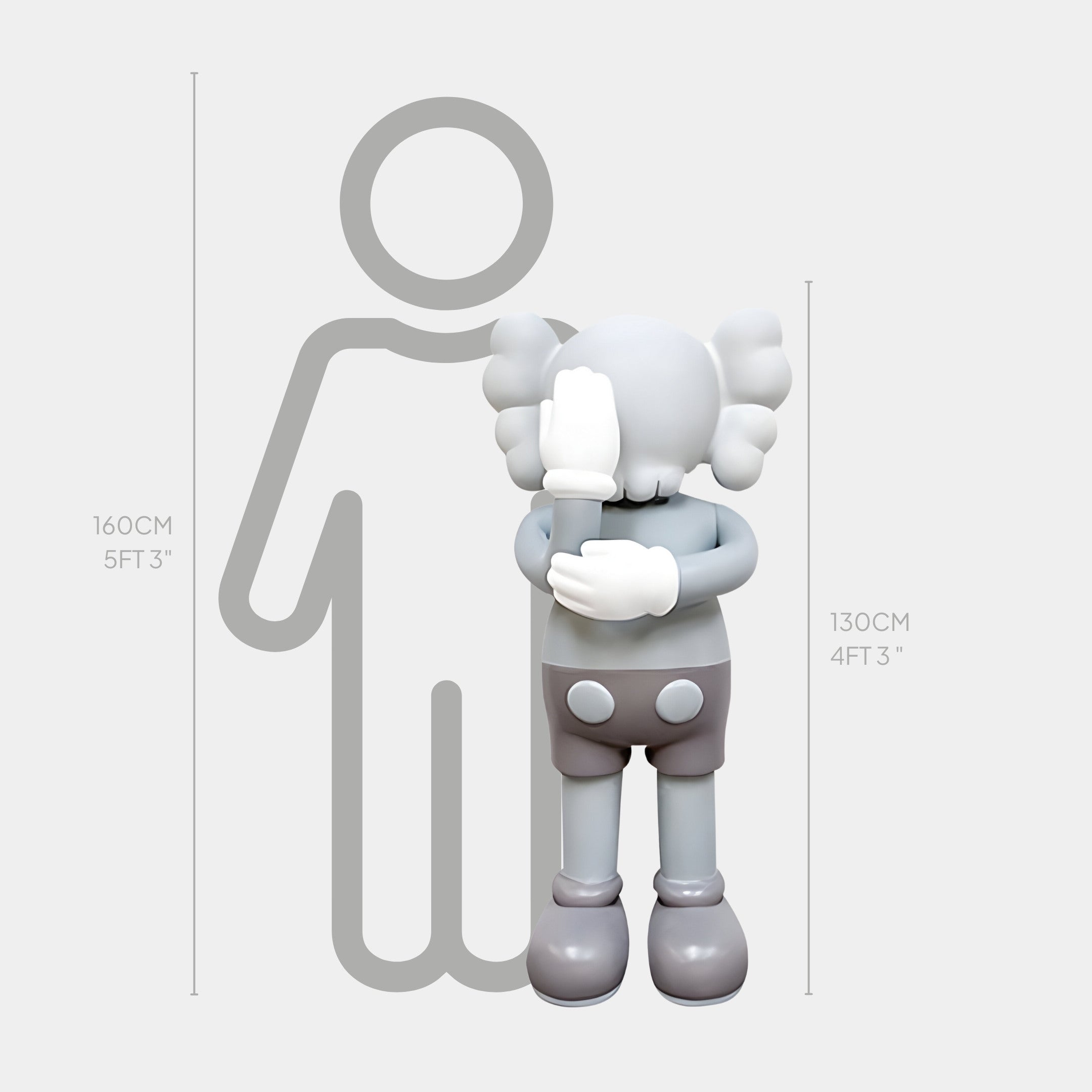 The Soft Grey Iconify III Dance Sculpture by Giant Sculptures is a 130 cm (4 ft 3 in) gray cartoon-like statue with large gloves and rounded ears covering its face, embodying contemporary art. It stands next to an outlined humanoid figure that measures 160 cm (5 ft 3 in).