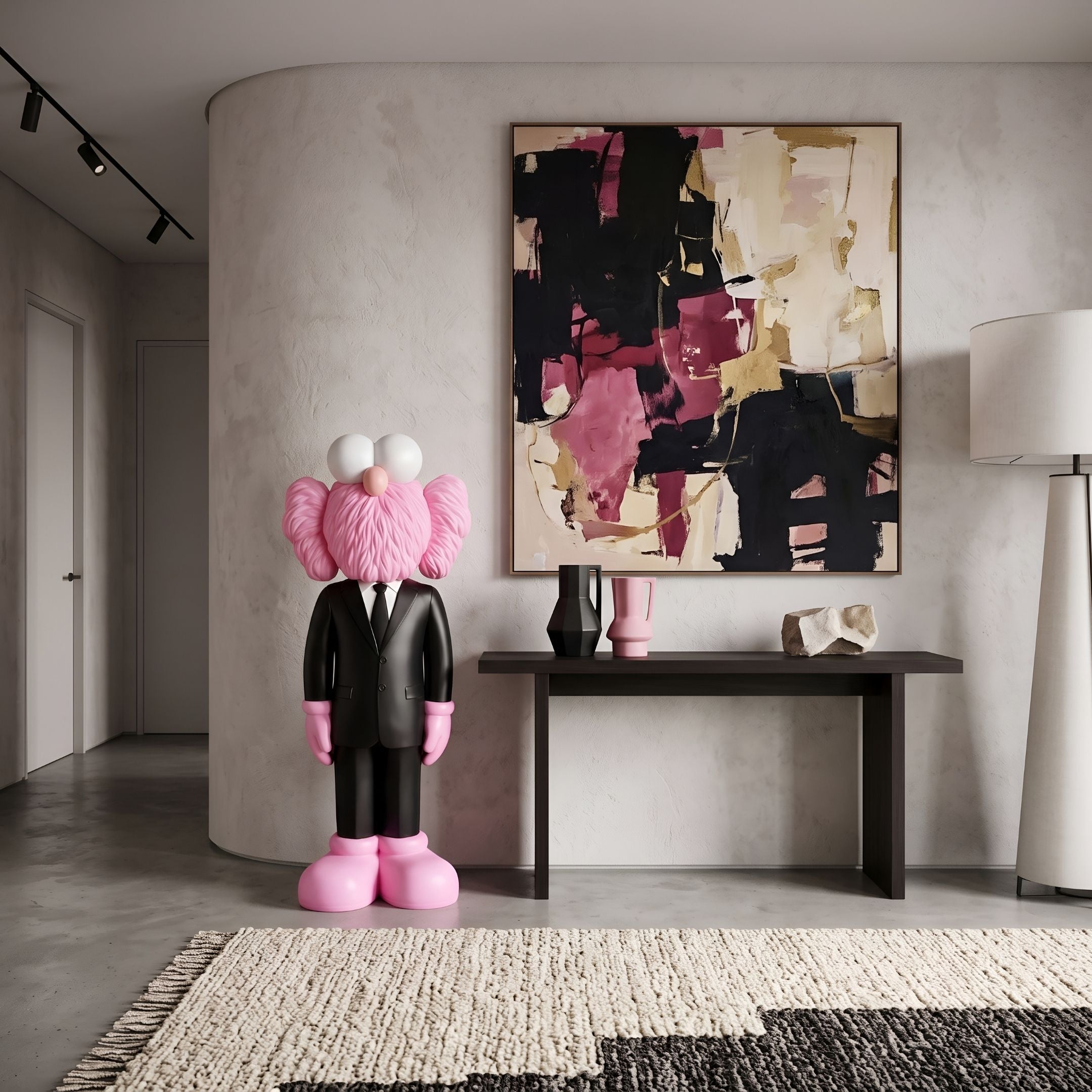 Black Suit Iconify CEO Sculpture, 130cm, pink figure in tailored black suit, displayed in an entryway beside a dark console table and abstract wall art.