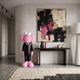 Black Suit Iconify CEO Sculpture, 130cm, pink figure in tailored black suit, displayed in an entryway beside a dark console table and abstract wall art.