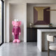 Deep Magenta Suit Iconify CEO Sculpture, 130cm, pink resin figure in a magenta suit, displayed in an alcove near a marble kitchen island.