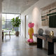 Sunbeam Yellow Suit Iconify CEO Sculpture, 130cm, yellow-suited figure with pink accents on a plinth in an entryway beside a console table and woven wall hanging.