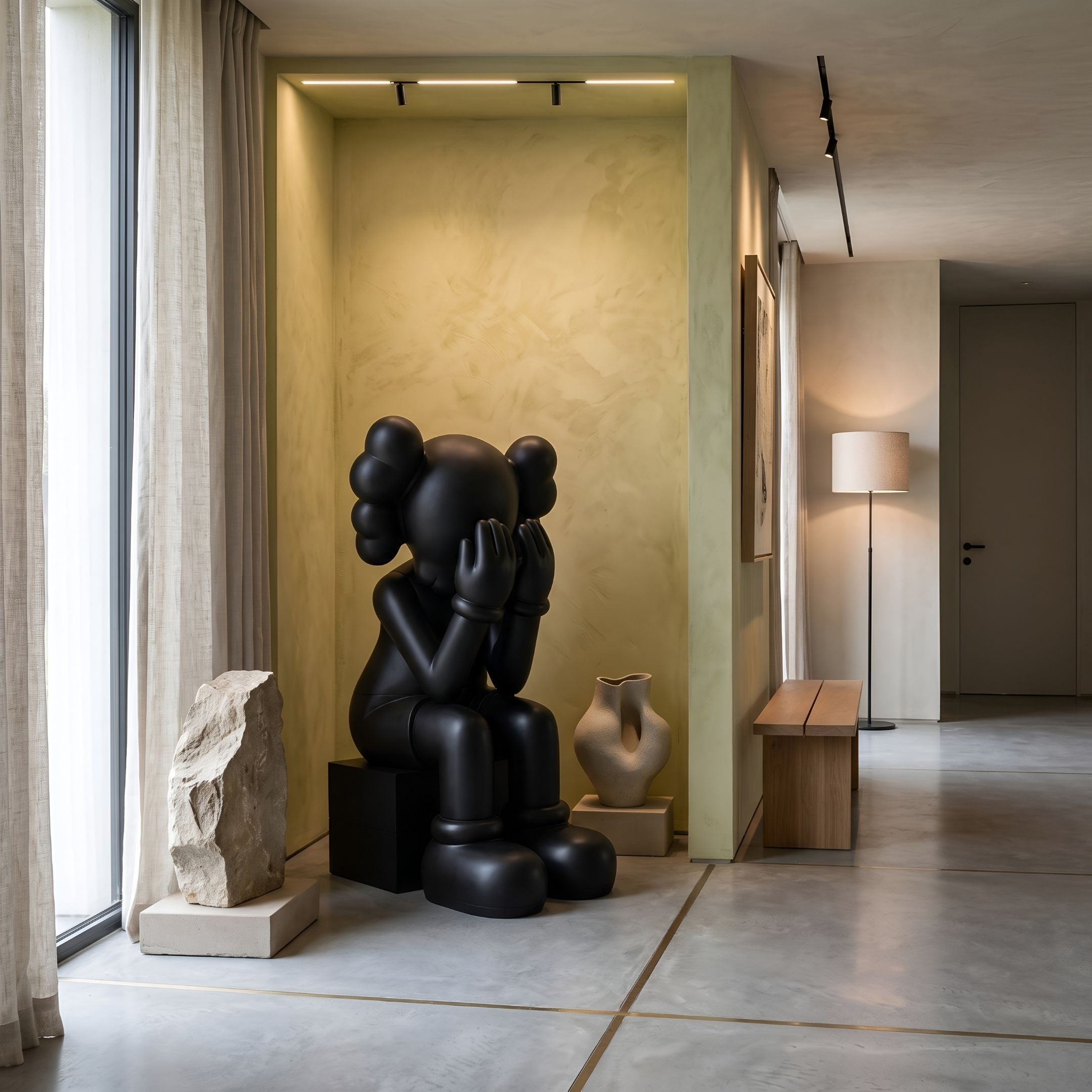 Midnight Black Iconify Melancholy Sitting Sculpture, 130cm, seated figure with hands over face, displayed in a living room alcove with a stone base and vase.