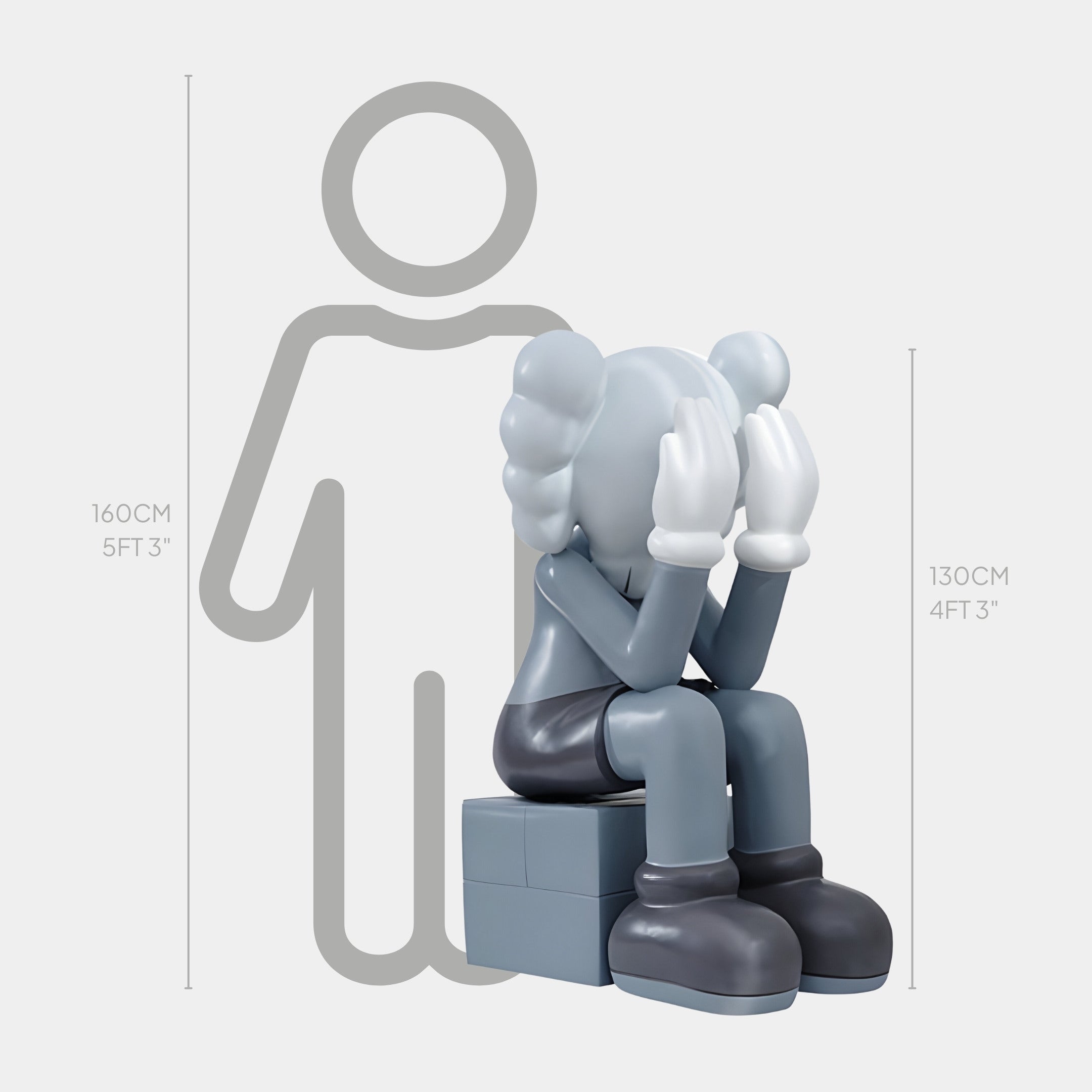 The Giant Sculptures Slate Grey Iconify Melancholy Sitting Sculpture - 130cm captures modern minimalism, concealing its face in gloved hands on a gray block. At 130cm (4ft 3in), it offers emotional depth next to a 160cm (5ft 3in) human silhouette, crafting a poignant scene.