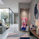 Petal Pink Iconify Melancholy Sitting Sculpture, 130cm, seated with hands covering its face, pink finish with blue shoes, displayed in a hallway alcove.