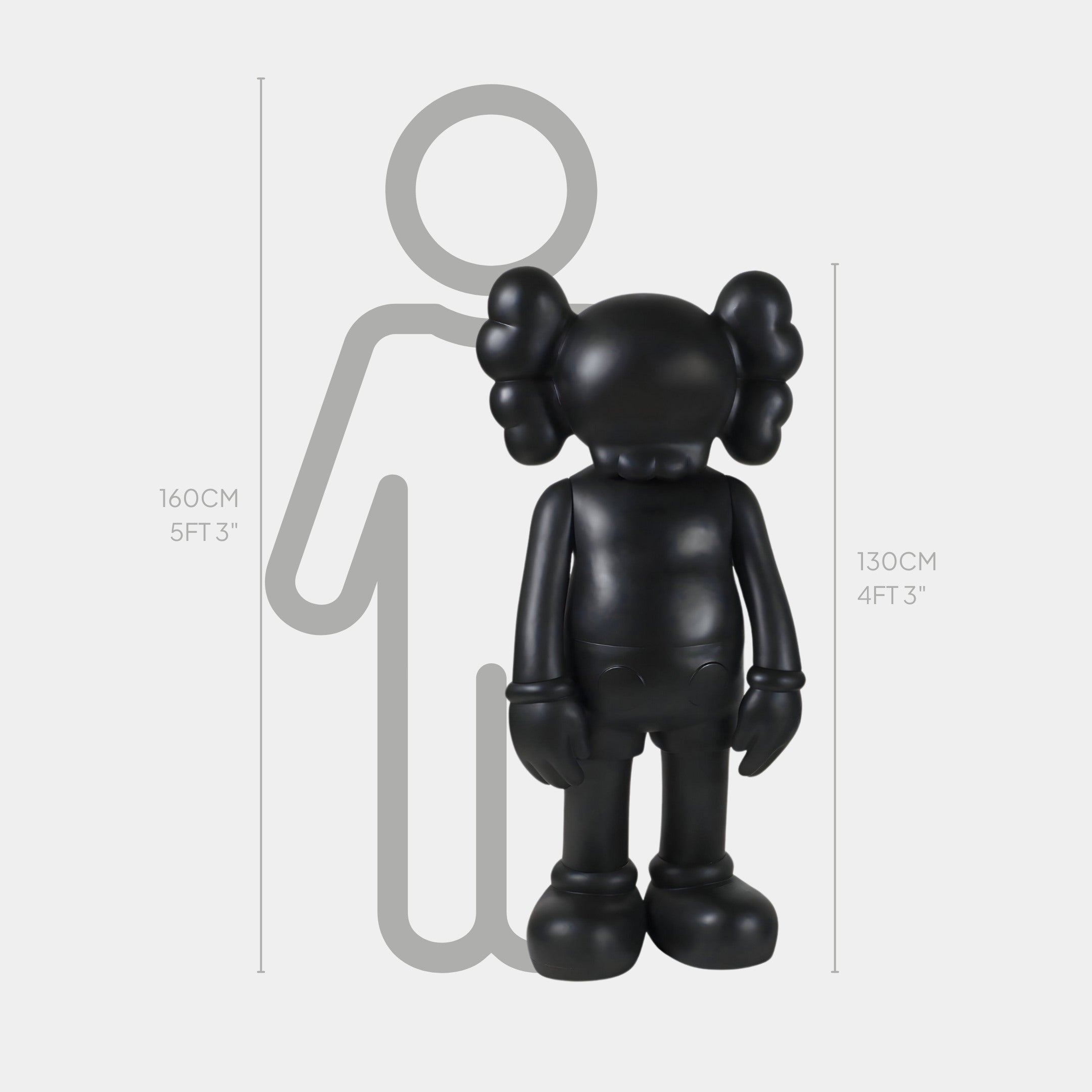 The Giant Sculptures Midnight Black Iconify Standing Sculpture, a 130cm (4ft 3in) cartoon-style black figure with distinct ears, stands beside a 160cm (5ft 3in) grey silhouette, seamlessly blending into modern interiors with its contemporary design.