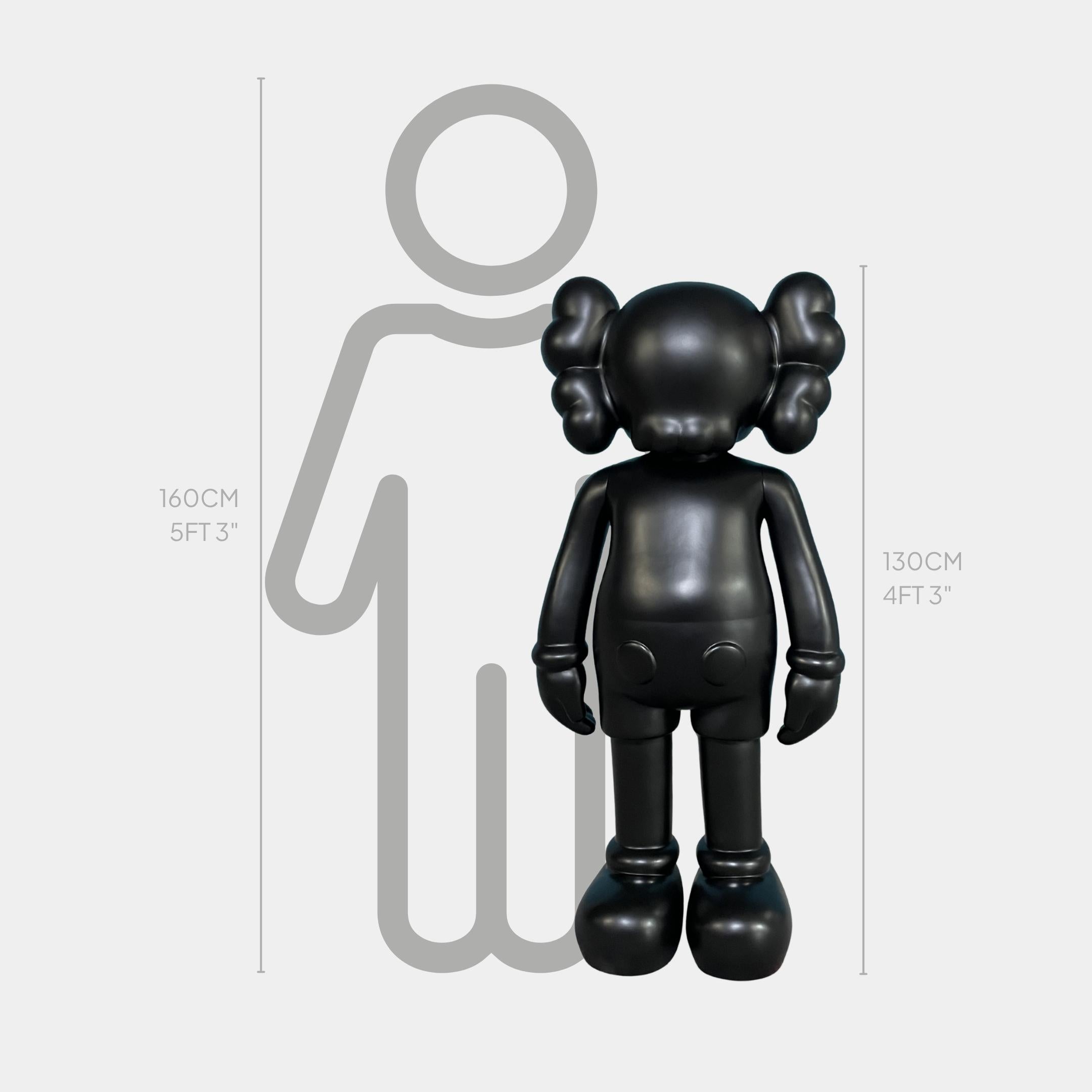 Midnight Black Iconify Standing Sculpture by Giant Sculptures, a 130cm matte black figure with rounded ears, shown beside a 160cm human silhouette for scale.