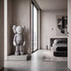 Soft Grey Iconify Standing Sculpture, 130cm, on a concrete base by a window in a bedroom with a dark bed and abstract wall art.