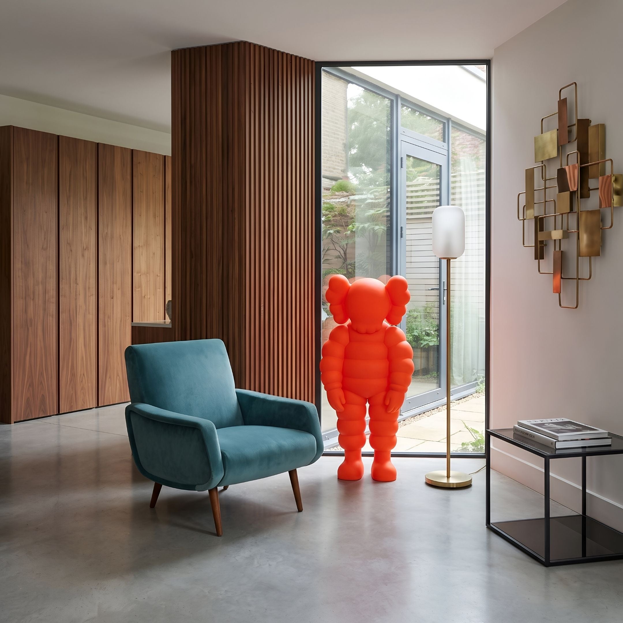 Fiery Orange Iconify Rollo Sculpture, 130cm, standing figure with rounded silhouette and ear-like details, in a living room beside a teal armchair and floor lamp.