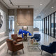 Royal Blue Iconify Rescuing Furry Sculpture, 135cm, resin figure bending over a blue furry character, displayed in a lounge with leather chairs and a coffee table.