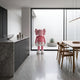 Soft Pink Iconify Standing Sculpture, 135cm, in a modern kitchen and dining space with grey cabinetry, marble island, and wooden dining chairs.