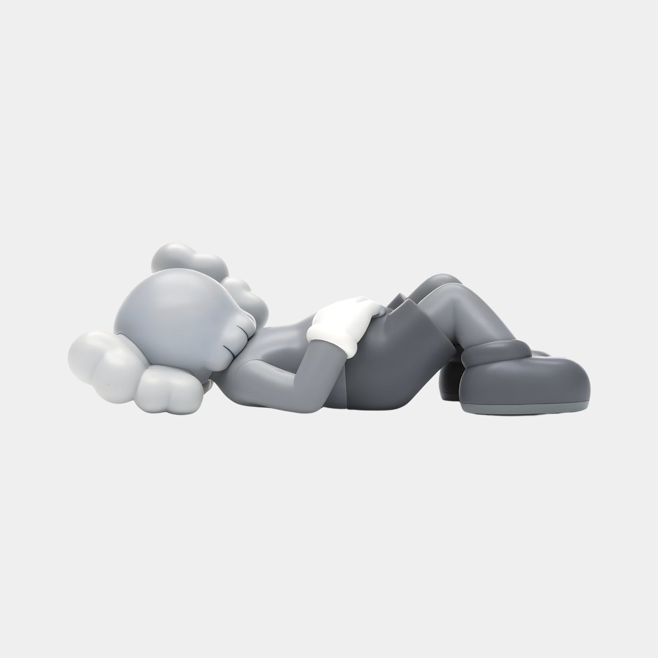 The Soft Grey Iconify Peace Figure by Giant Sculptures, a minimalist 14cm vinyl piece, features a gray hue with cloud-shaped ears and outstretched arms. It dons gloves, shorts, and shoes in soft gray tones against a white backdrop.