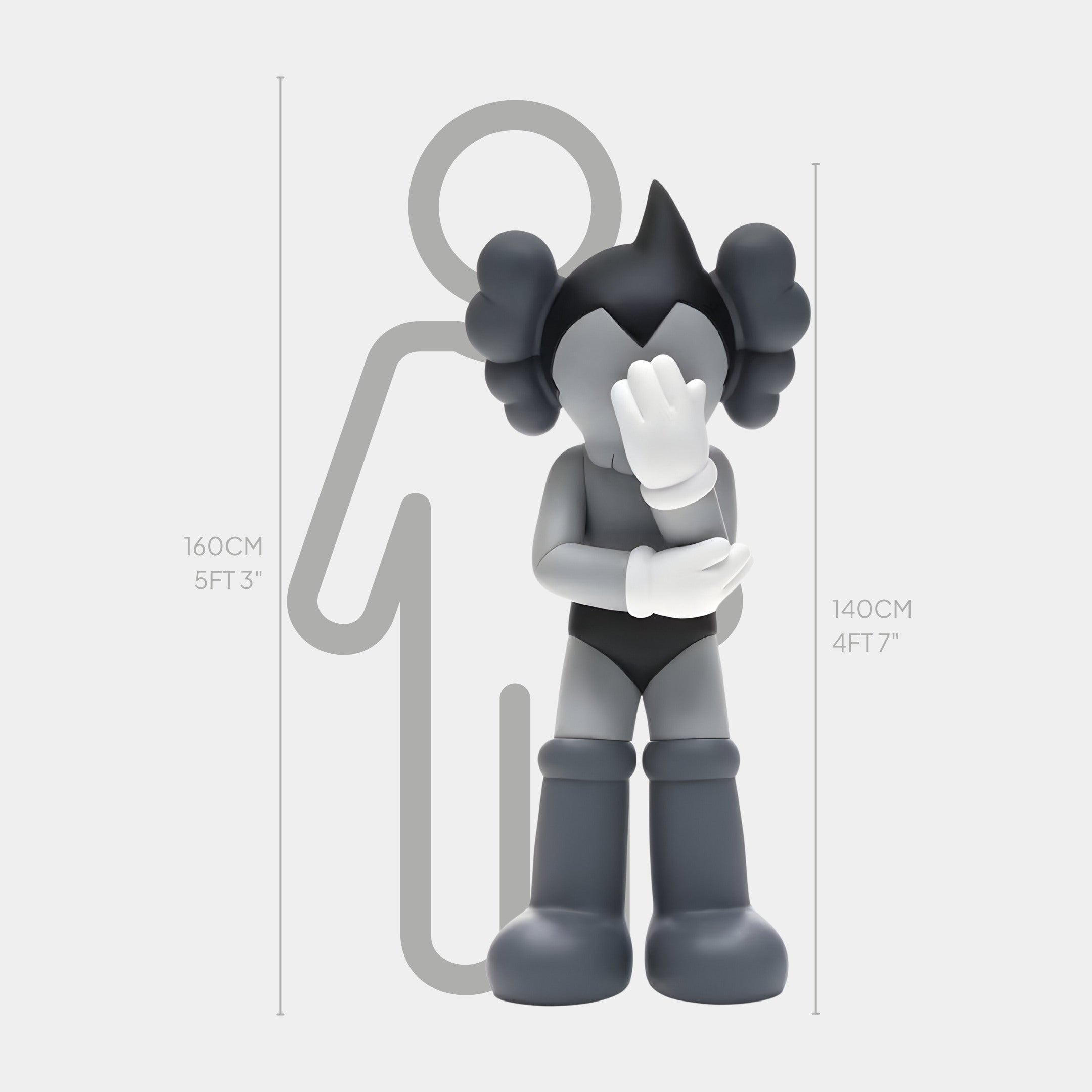 The Slate Grey Iconify Cosmic Boy Sculpture by Giant Sculptures, at 140 cm (4 ft 7 in), features a monochrome cartoon character with a shy pose, hand partially covering its face. It dons boots and a simple outfit next to a human silhouette to highlight its height.