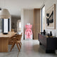 Petal Pink Iconify Furry Sitting Sculpture (140cm) on a white cube base in a dining room, beside a wood slat column and dark sideboard.