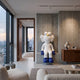 White & Blue Iconify Furry Sitting Sculpture, 140cm, seated on a concrete wall niche in a living room beside a wooden sideboard and city-view window.