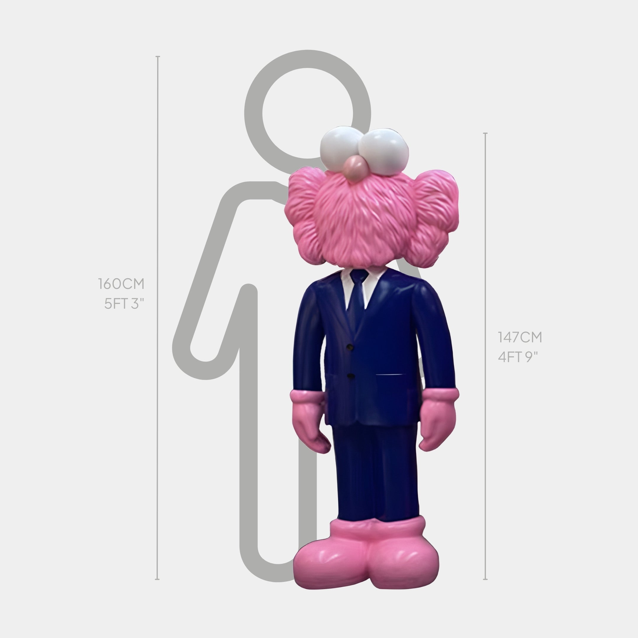 The Deep Navy Blue Suit Iconify CEO Sculpture by Giant Sculptures features a pink cartoonish figure with large eyes and furry ears. The contemporary design, standing 147cm (4ft 9in) tall, is placed next to a height chart against a 160cm (5ft 3in) outline, evoking pop-art fun.