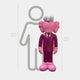 The Deep Magenta Suit Iconify CEO Sculpture by Giant Sculptures, standing at 147cm, features a pink cartoon character with large eyes and pink shoes. It exudes contemporary elegance in front of a height chart alongside a gray human outline, resembling a whimsical CEO.