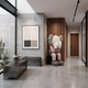 Hazelnut Brown Iconify Melancholy Sitting Sculpture, 163cm, seated figure covering face, in a hallway with wood paneling, concrete wall, and framed art.