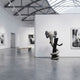 Ash Grey Iconify Snake Sculpture, 176cm, displayed in a gallery with grey and black intertwined figures on a black base near framed wall art.