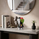 Slate Grey Iconify Monkey Figure (18cm) on a console table, dual-faced design with grey skull-like side and green anatomical side, styled near books, stones, and a mirror.