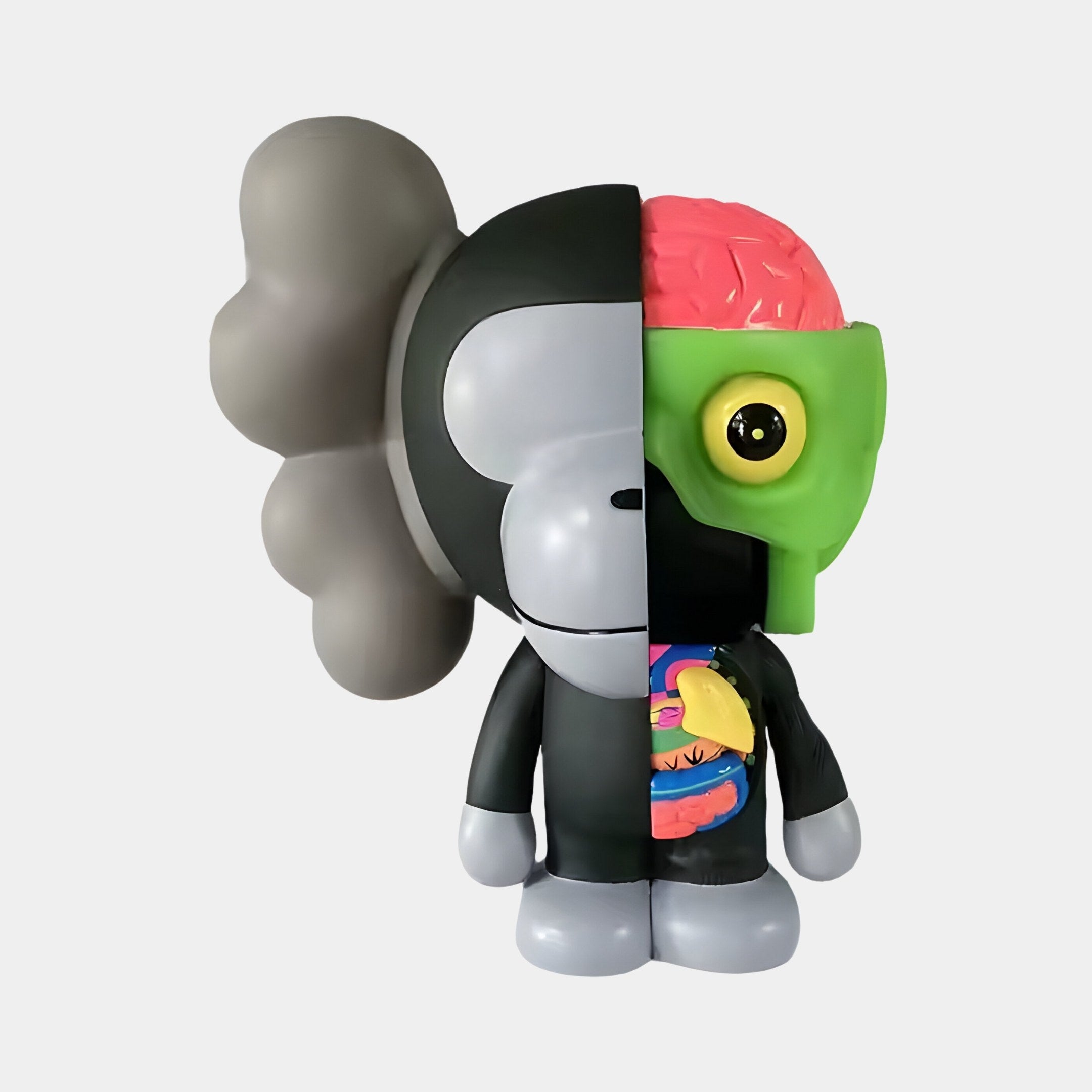 The 18cm Slate Grey Iconify Monkey Figure by Giant Sculptures presents a bold design, with one side displaying an industrial gray skull-like look and the other showcasing vivid anatomical details, including a green face and large round eyes on a white background.