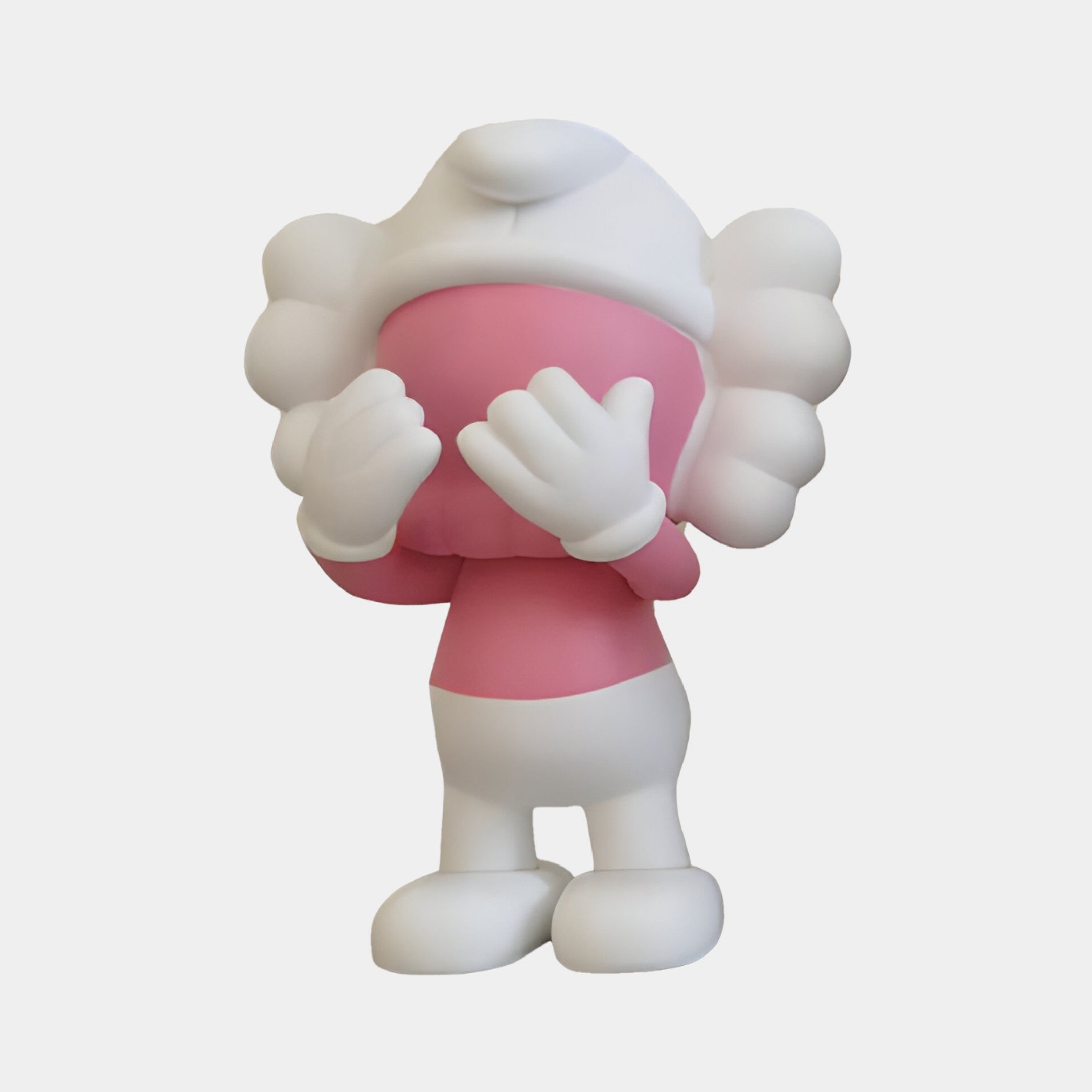 Discover the Petal Pink Iconify Peekaboo Figure by Giant Sculptures. This 20cm figure has a cartoonish character with a white round head, large eyes, and playfully covers its mouth with its hands. With white limbs and large feet, it adds whimsy to modern interiors.