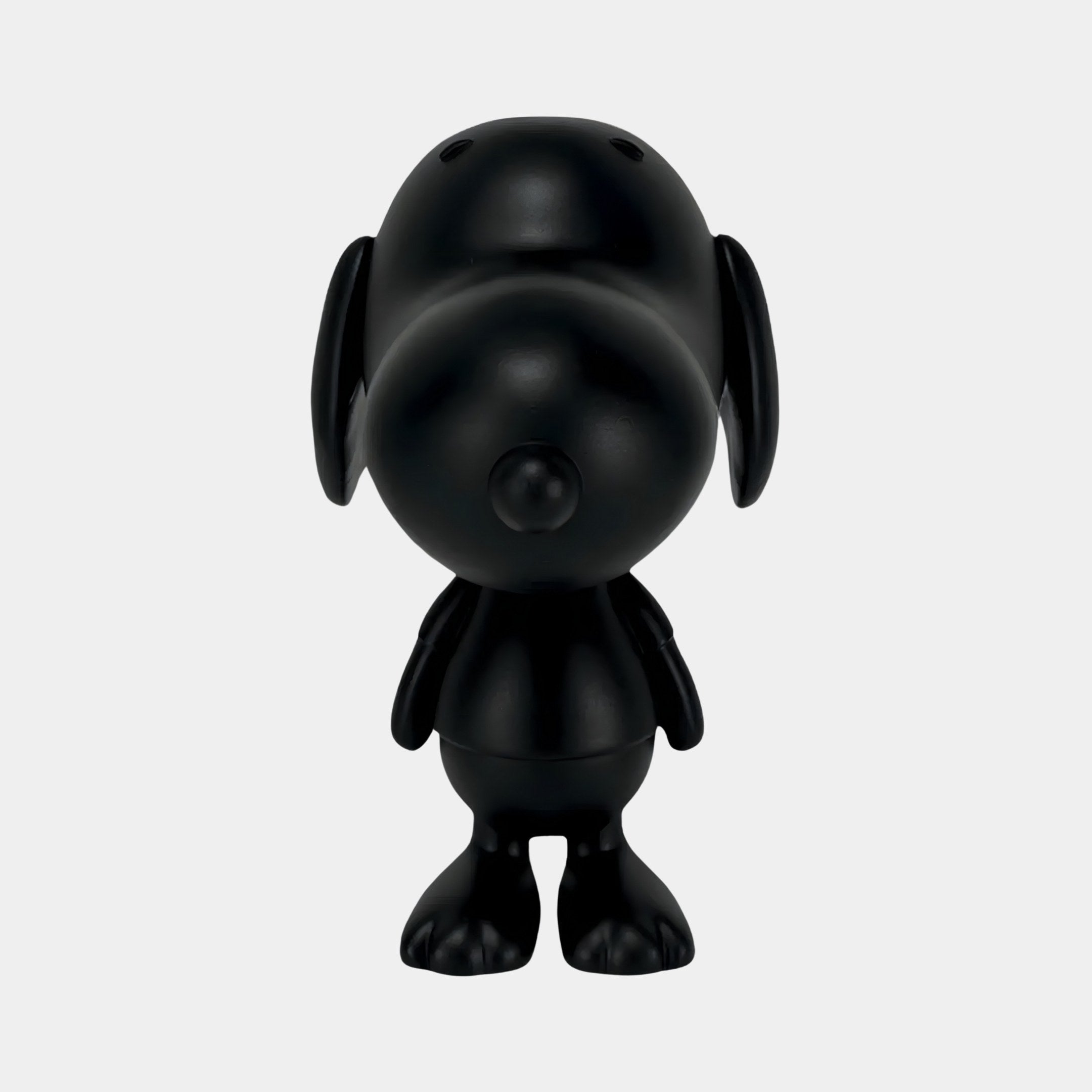 The 20cm Obsidian Black Iconify Puppy Figure by Giant Sculptures is a minimalist black vinyl cartoon dog with large ears, a round nose, and simplified limbs. It stands facing forward on a plain white background, capturing modern minimalism.