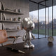 Titanium Slate Iconify Puppy Figure, 20cm silver metallic puppy sculpture on a dark desk in an office with bookshelves and floor-to-ceiling windows.
