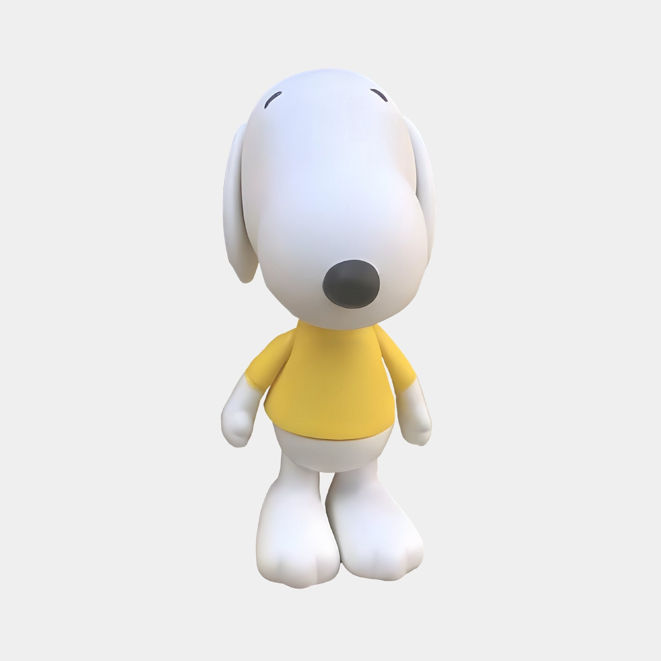 The White Iconify Puppy Figure by Giant Sculptures, standing at 20cm with a white body and black nose in a yellow shirt, sits against a plain light gray background, making it a perfect decorative piece for any modern setting.