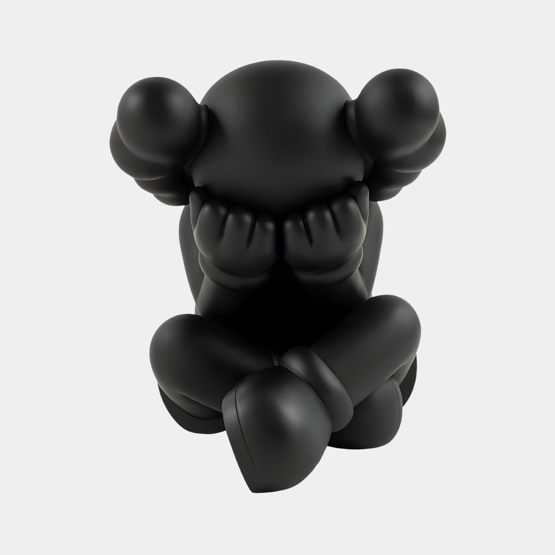 The Midnight Black Iconify Sorrow Figure by Giant Sculptures, a minimalist piece, features a stylized figure with large round ears sitting despondently with its head in hands and legs crossed against a white background, embodying modern contemporary art.