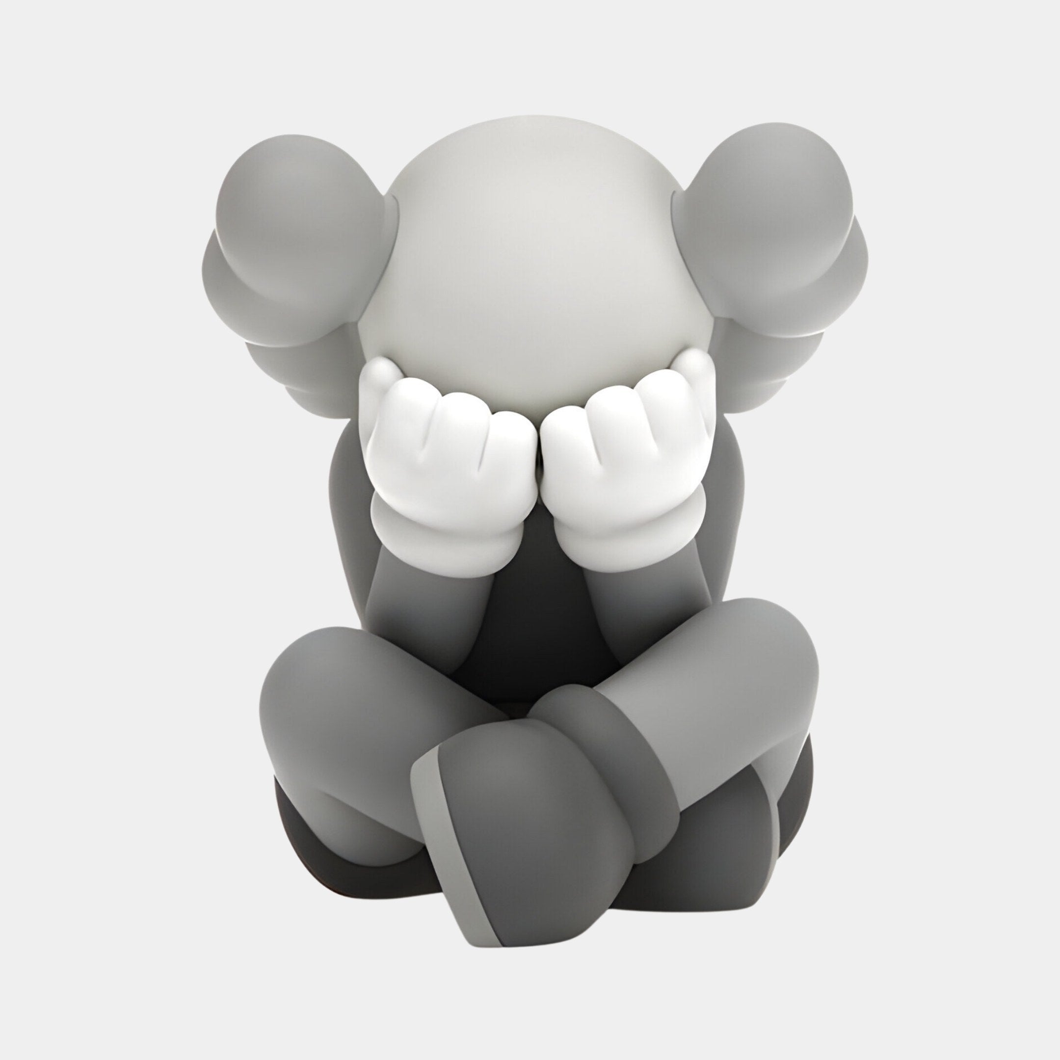 The 20cm Soft Grey Iconify Sorrow Figure by Giant Sculptures, a grayscale character with large ears, sits with knees up and gloved hands covering its face. It evokes distress and blends into contemporary interiors with abstract artistry.