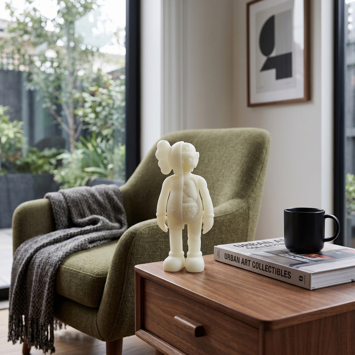 Ivory Iconify Anatomy Figure - 20cm by Giant Sculptures displayed on a wooden side table beside a green armchair, showing its split anatomical design.